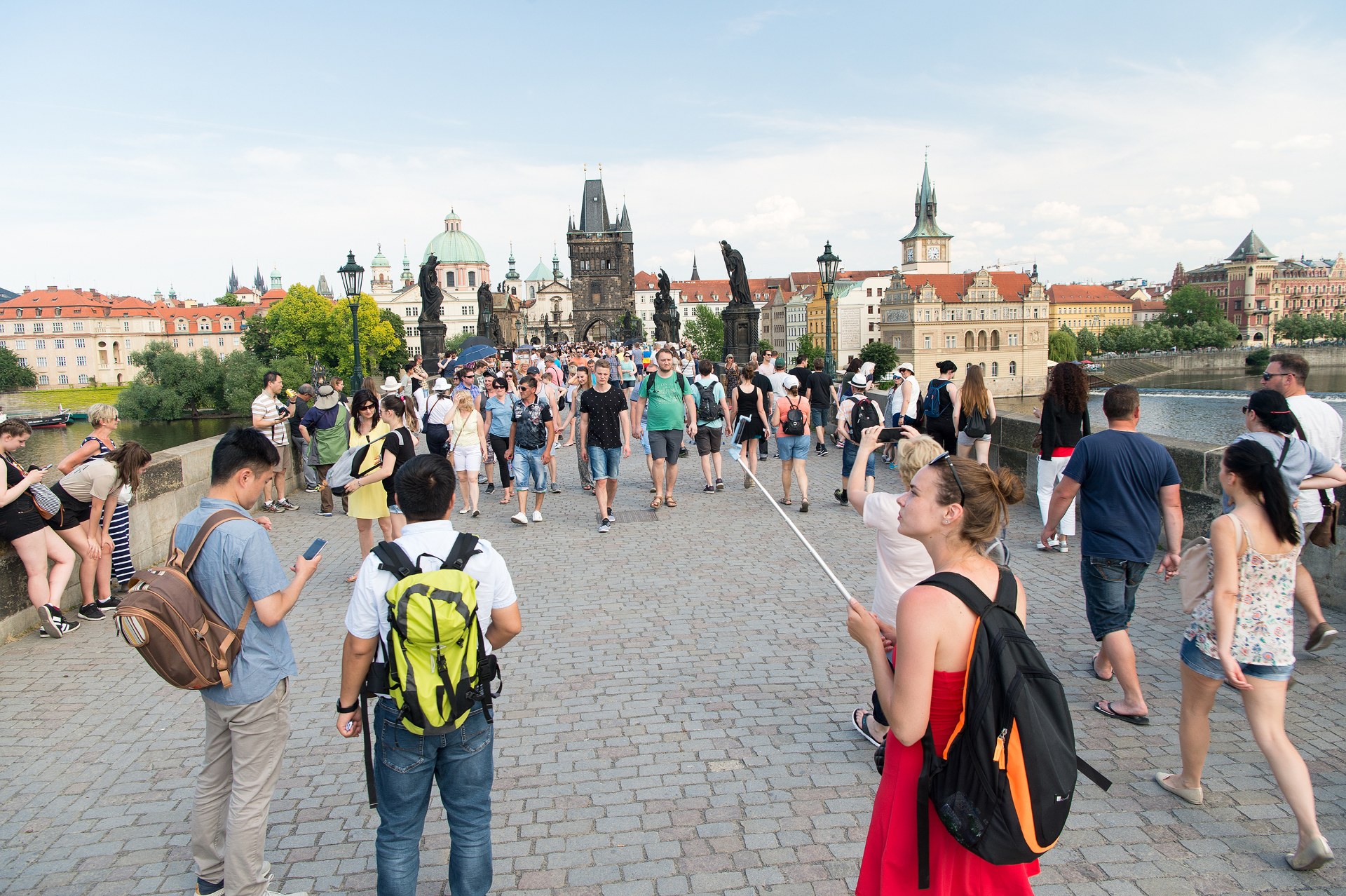 Ragazzi con lo zaino che attraversano il Ponte Carlo a Praga, con la torre del ponte della Città Vecchia alle spalle
